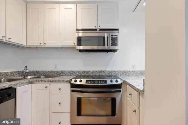 a kitchen with granite countertop white cabinets and stainless steel appliances