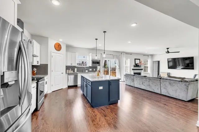 a kitchen with stainless steel appliances granite countertop a refrigerator a stove top oven a sink dishwasher and wooden floor