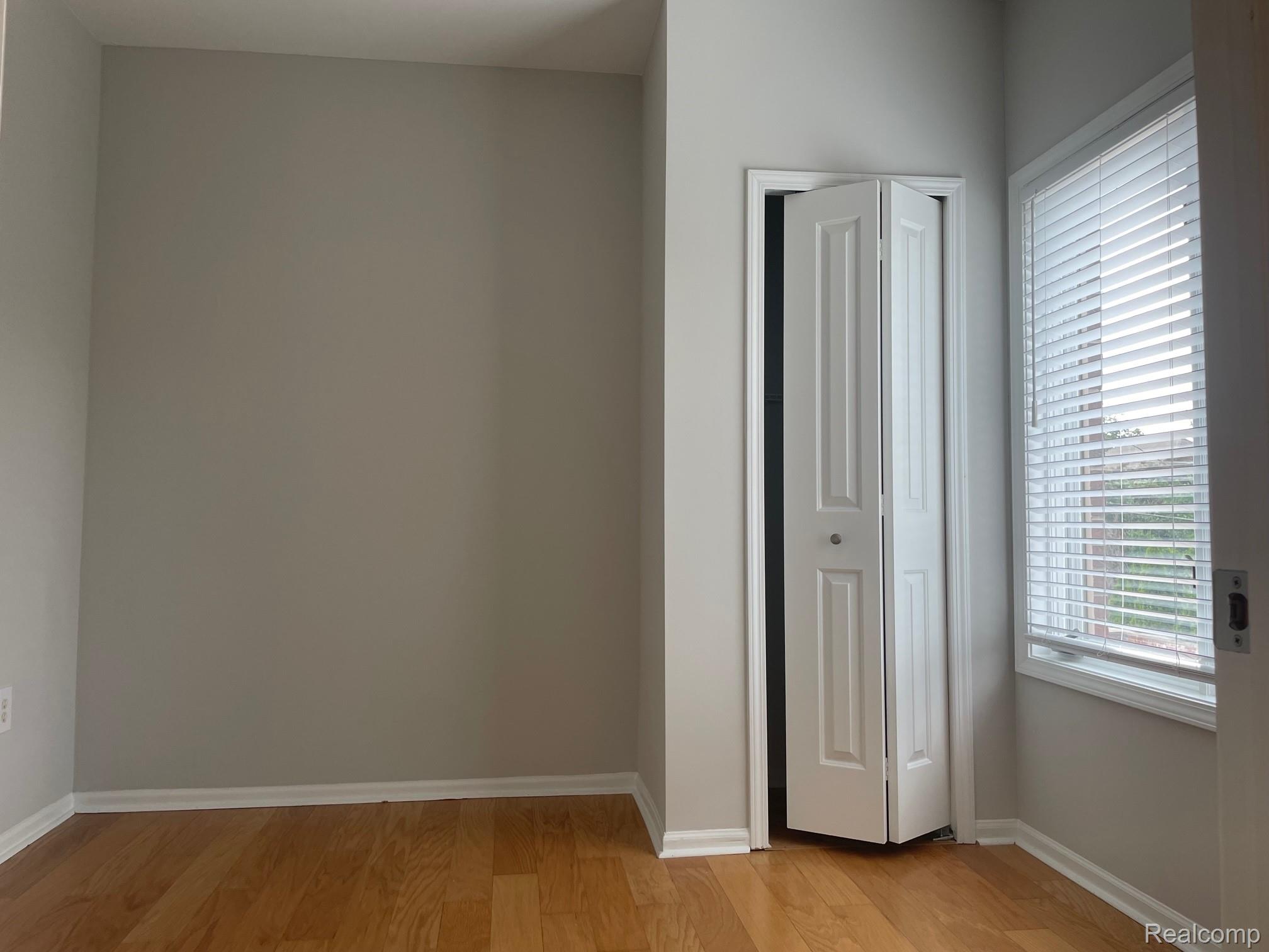 2727 East Maple Road Birmingham, MI 48009 - Photo 24 of 29 Wood-finish flooring, neutral wall tones, white trim, and a window with blinds