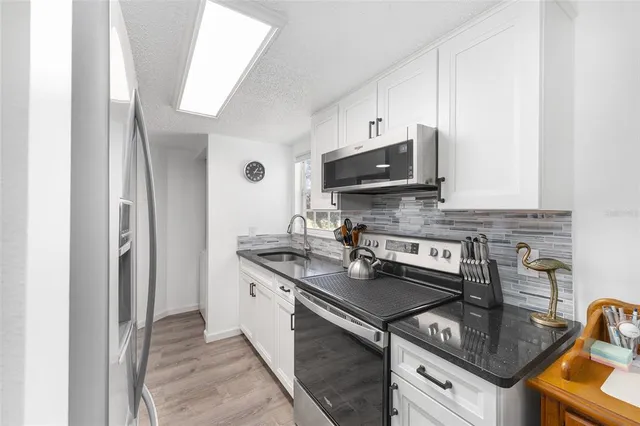 a kitchen with stainless steel appliances granite countertop a sink stove and refrigerator