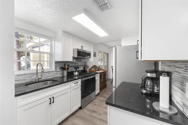 a kitchen with kitchen island granite countertop a sink appliances cabinets and a counter top space