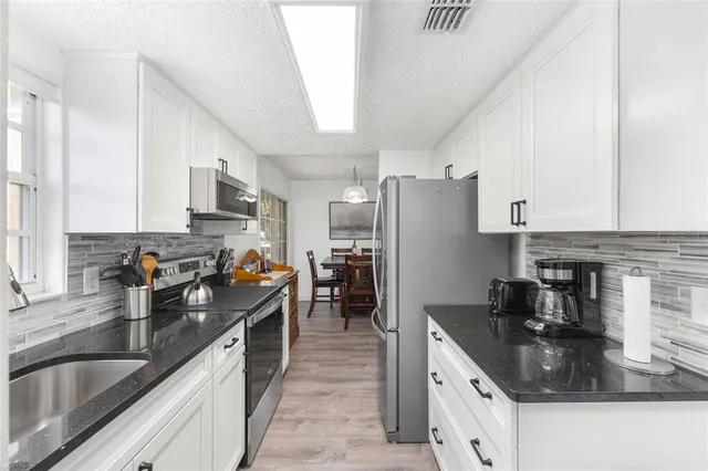 a kitchen with kitchen island granite countertop a sink a counter top space stainless steel appliances and cabinets