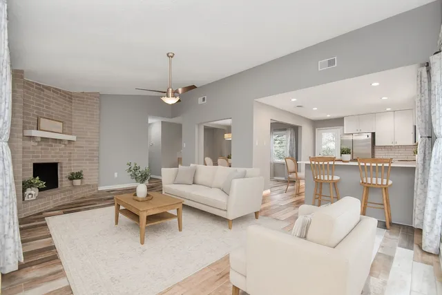a living room with furniture a fireplace and a dining table with kitchen view