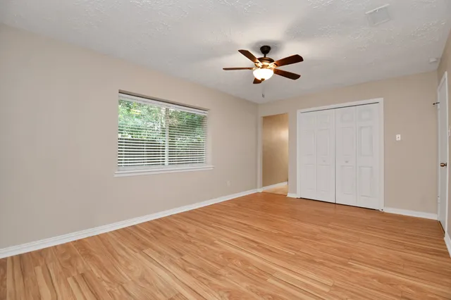 a view of empty room with wooden floor and fan