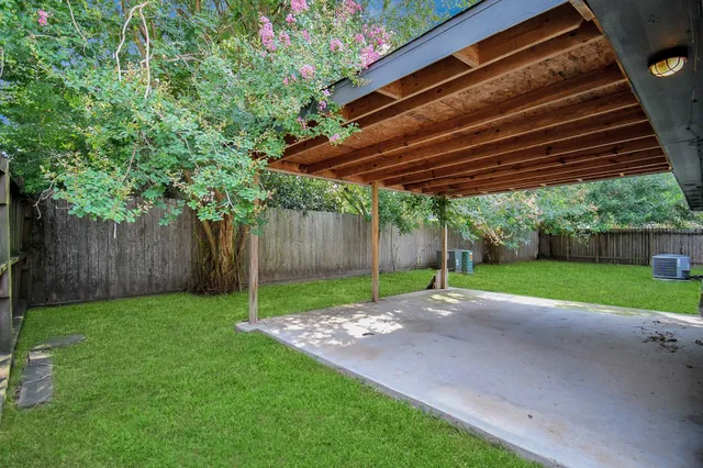a view of a backyard with wooden fence and a large tree
