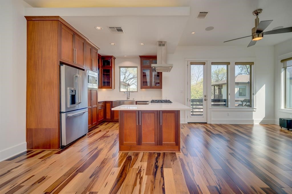 a kitchen with stainless steel appliances granite countertop a refrigerator a stove top oven a sink dishwasher and white cabinets with wooden floor