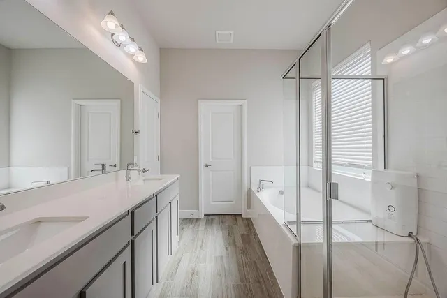 a spacious bathroom with a double vanity sink a large mirror and shower