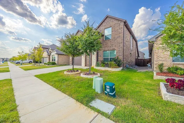 a front view of a house with garden and tree