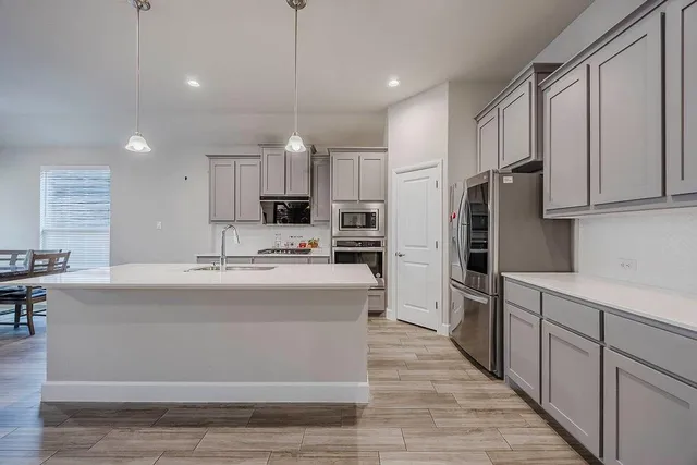 a view of kitchen with stainless steel appliances granite countertop a stove oven and a refrigerator with white cabinets