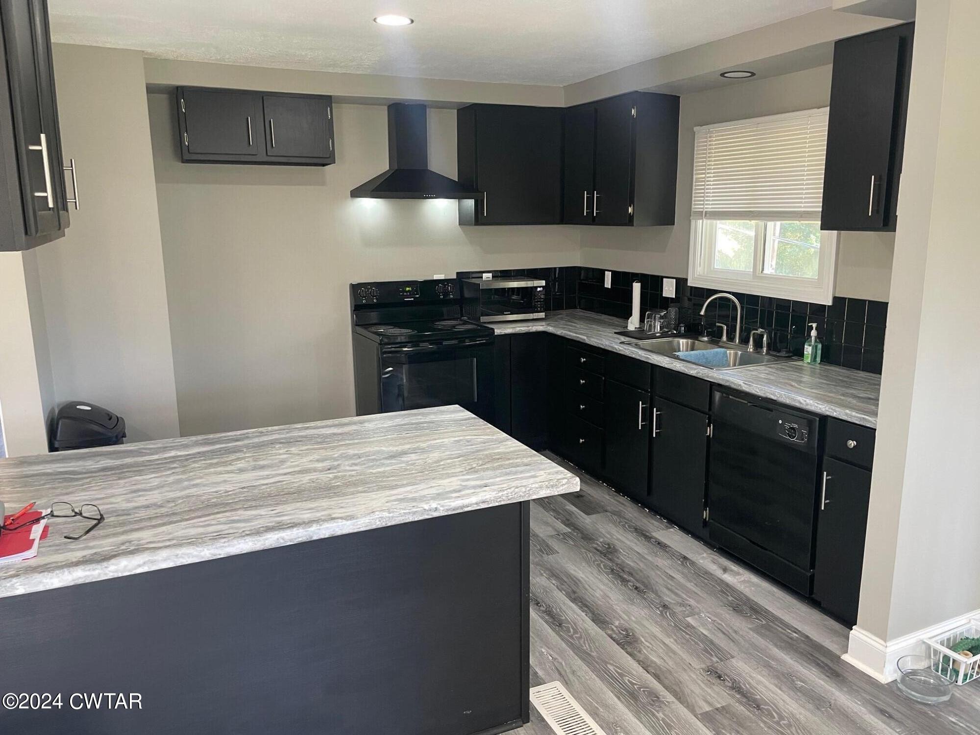 113 Ebenezer Road Mercer, TN 38392 - Photo 5 of 36 a kitchen with a sink dishwasher a stove and black white cabinets