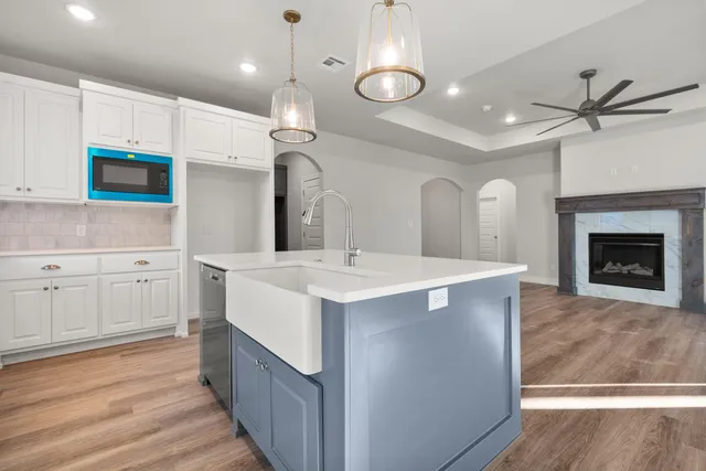 a large white kitchen with a sink and dishwasher a stove with wooden floor