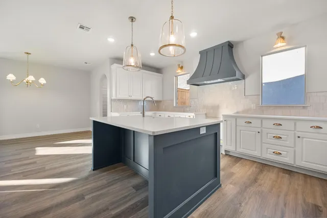 a kitchen with a sink chandelier and wooden floor