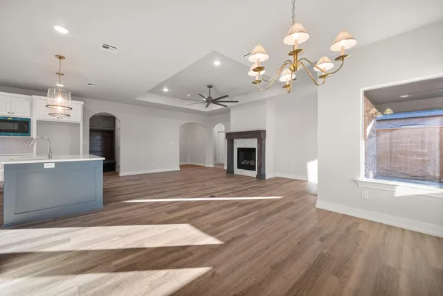 a view of a livingroom with a fireplace a chandelier and wooden floor