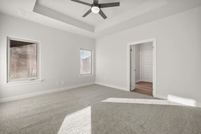 an empty room with windows and fan