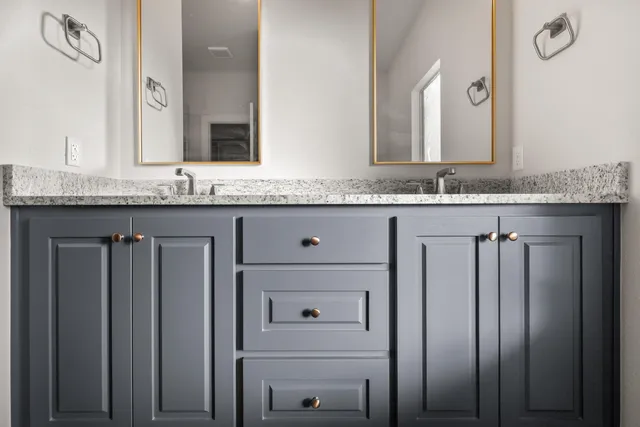 a bathroom with a granite countertop sink and a mirror