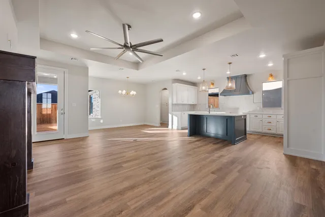 an empty room with wooden floor and kitchen view