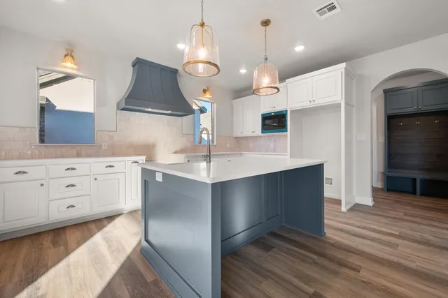 a kitchen with kitchen island granite countertop a sink and a stove