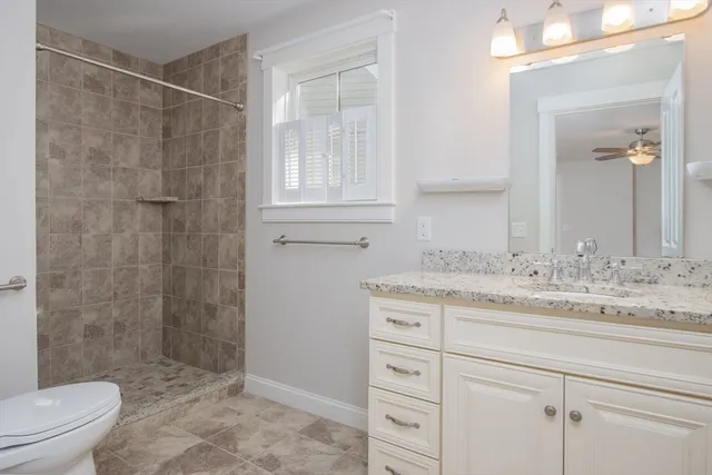 a bathroom with a granite countertop sink a toilet and shower