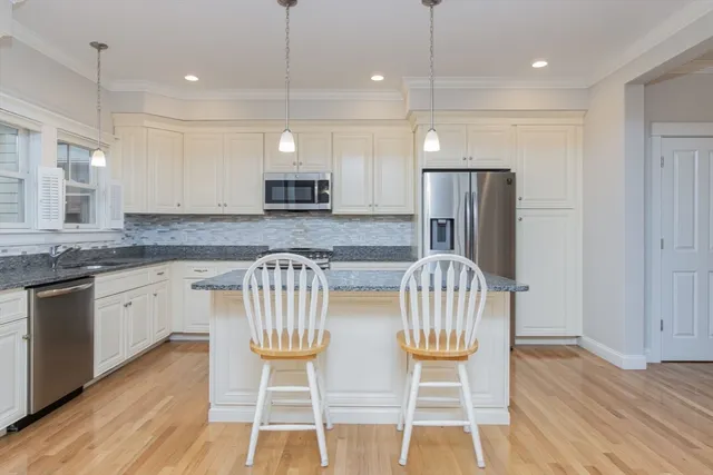 a kitchen with stainless steel appliances granite countertop a kitchen island hardwood floor and a sink