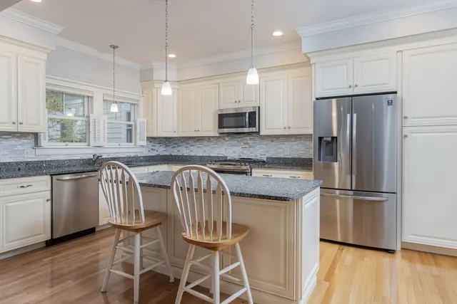 a kitchen with granite countertop stainless steel appliances a refrigerator microwave and wooden floor