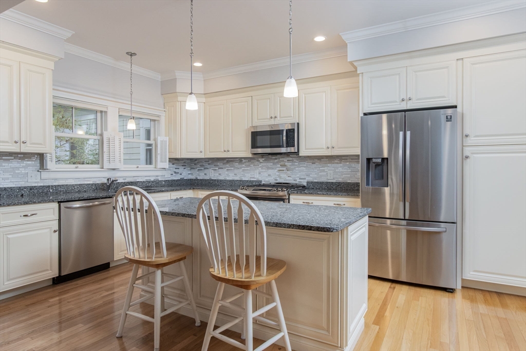21 A Blacksmith Row, Unit 21 Groton, MA 01450 - Photo 7 of 42 a kitchen with granite countertop stainless steel appliances a refrigerator microwave and wooden floor