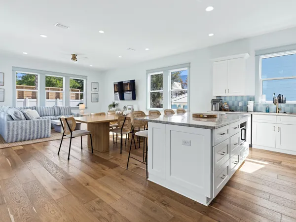 a living room with furniture kitchen view and a dining table with wooden floor