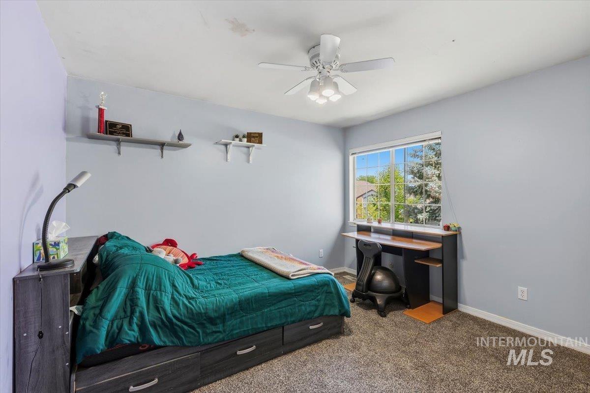 8001 West Innsbrook Court Boise, ID 83704 - Photo 27 of 39 Carpeted room with a ceiling fan light fixture, a large window, a built-in desk, and wall-mounted shelving