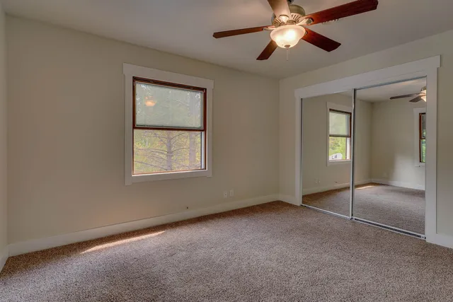 a view of an empty room with window and chandelier fan