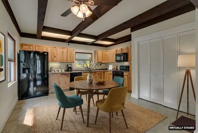 a dining room with stainless steel appliances granite countertop a table chairs and a refrigerator