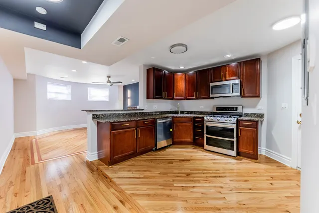 a kitchen with stainless steel appliances kitchen island granite countertop a stove and a sink