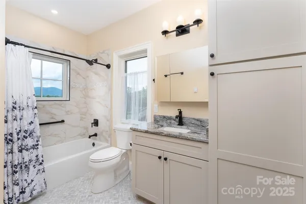 a bathroom with a granite countertop sink a toilet and shower