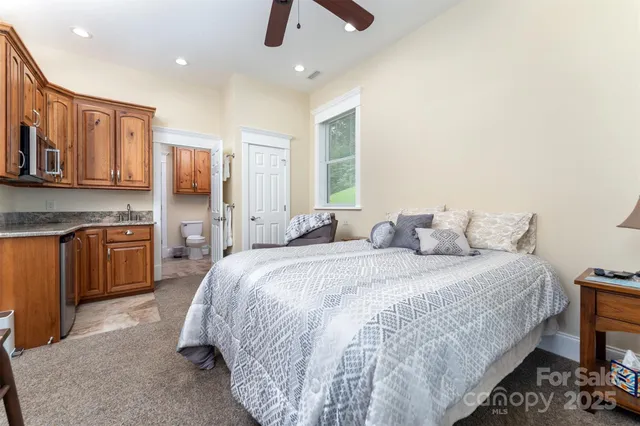 a spacious bedroom with a bed a dresser and a chandelier