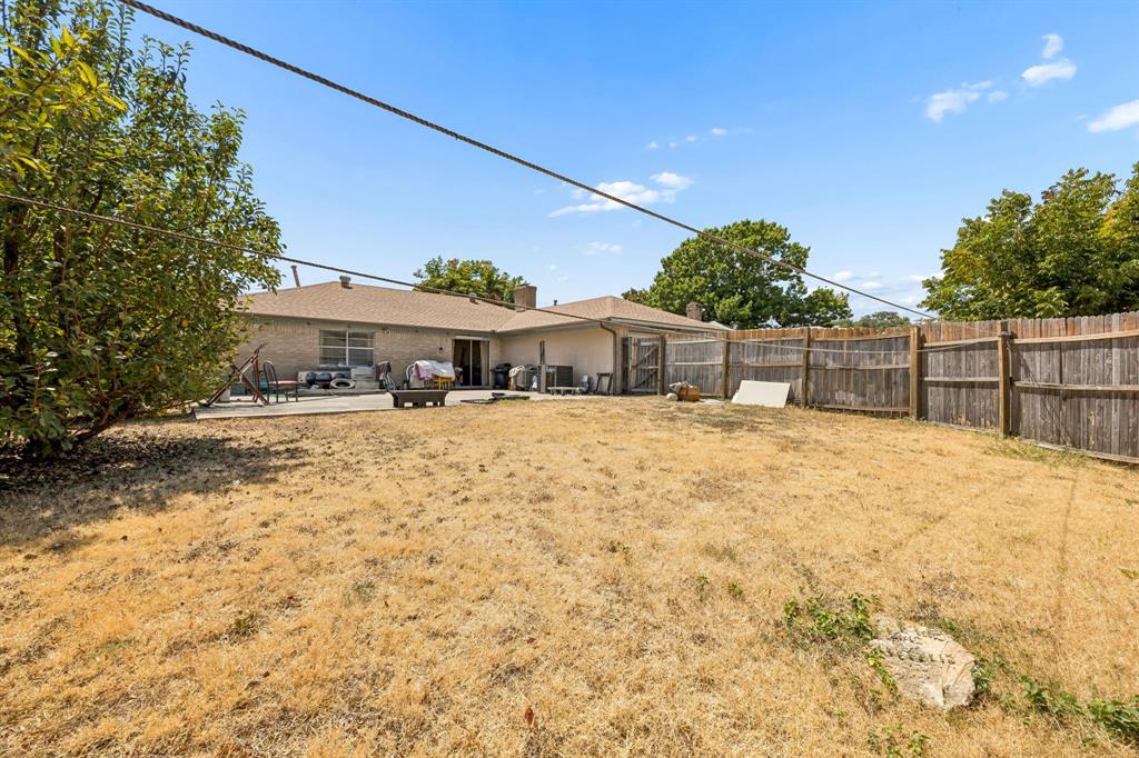 1701 East Spring Valley Road Richardson, TX 75081 - Photo 28 of 28 Expansive backyard with a wooden fence, concrete patio, and mature trees