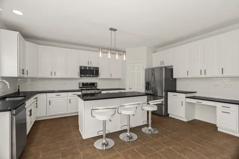 a kitchen with a sink a stove a refrigerator and white cabinets