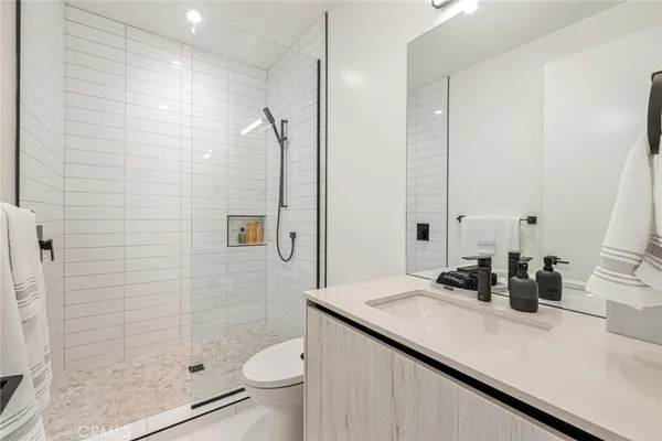 a bathroom with a granite countertop sink a toilet a mirror and shower