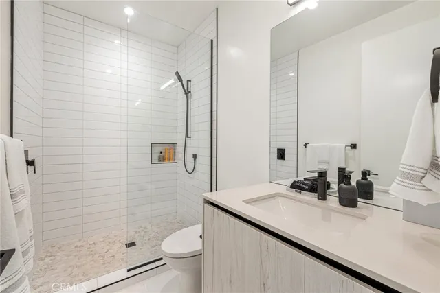 a bathroom with a granite countertop sink a toilet a mirror and shower