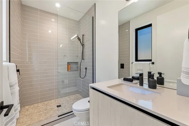 a bedroom with a large bed a potted plant and a dresser next to a window