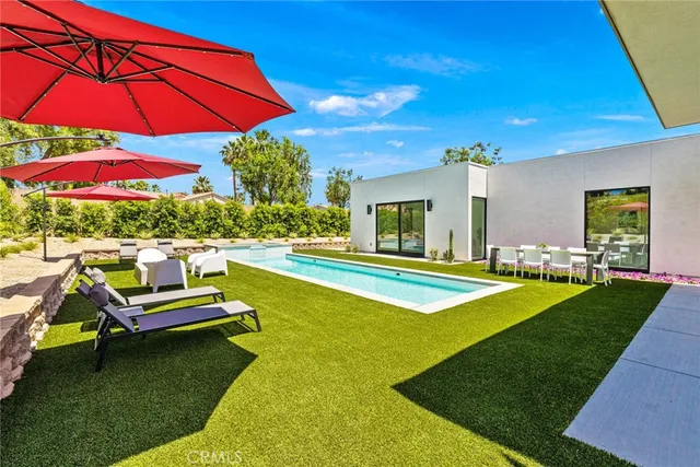 a view of a swimming pool with a table and chairs under an umbrella