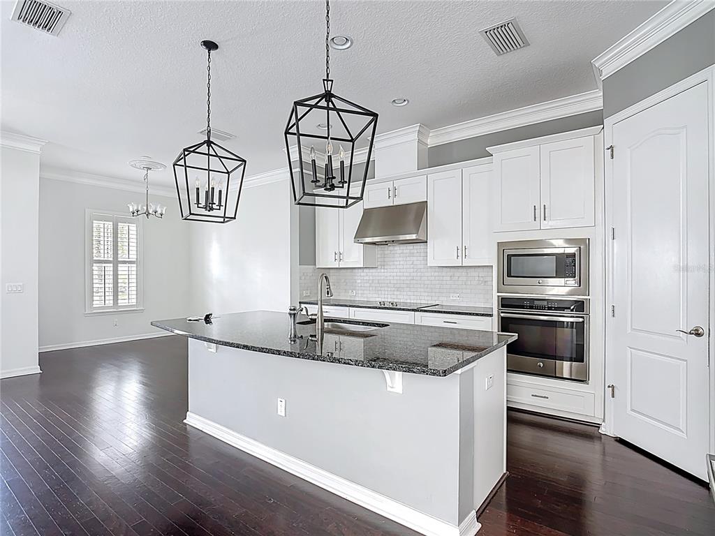 1513 Resolute Street Celebration, FL 34747 - Photo 17 of 43 a kitchen with stainless steel appliances granite countertop a stove and white cabinets