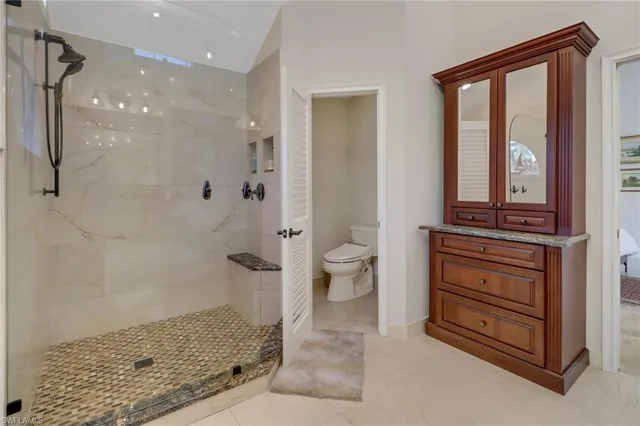 a bathroom with a granite countertop sink a toilet and shower