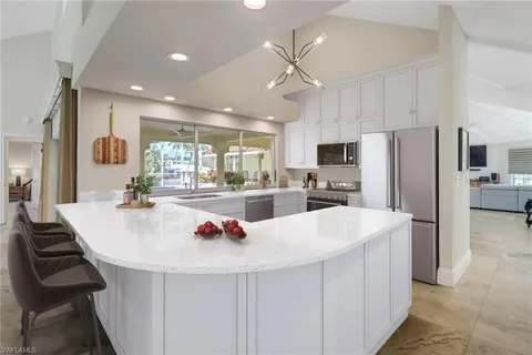 a kitchen with refrigerator a sink and chairs