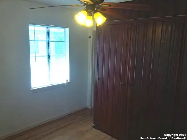 a view of empty room with window and chandelier fan
