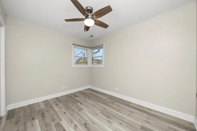 an empty room with wooden floor and ceiling fan