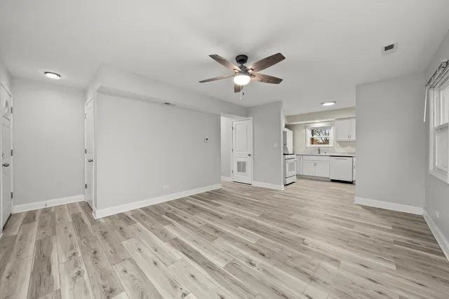 a view of empty room with wooden floor and fan