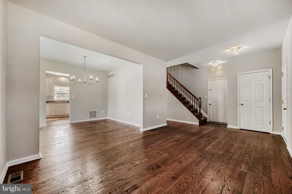 a view of an empty room with wooden floor and stairs