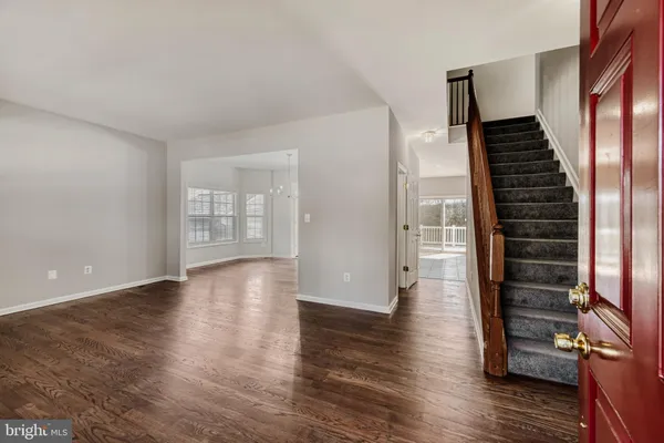 a view of an empty room with wooden floor and stairs