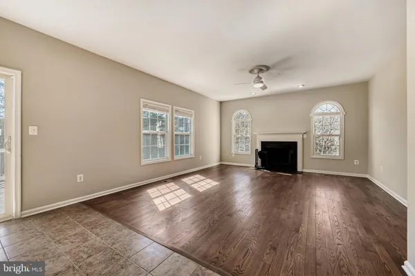 an empty room with wooden floor fireplace and windows