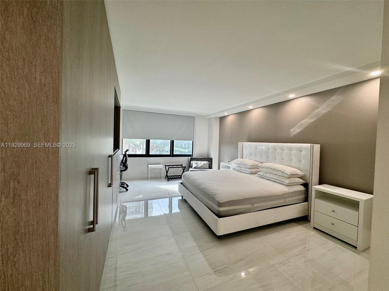 9801 Collins Avenue, Unit 5U Bal Harbour, FL 33154 - Photo 23 of 62 a spacious bedroom with a bed and a night stand