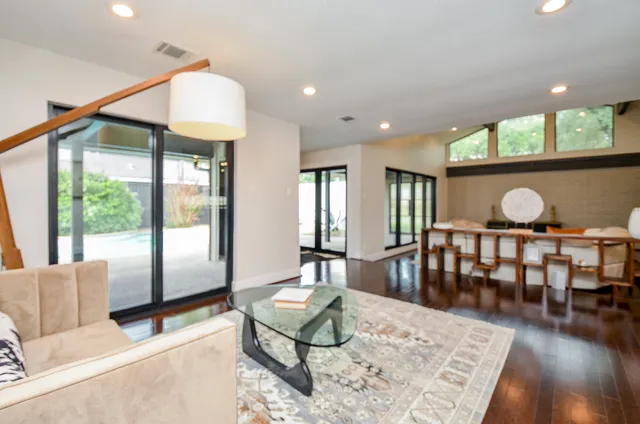 a living room with furniture a large window and wooden floor