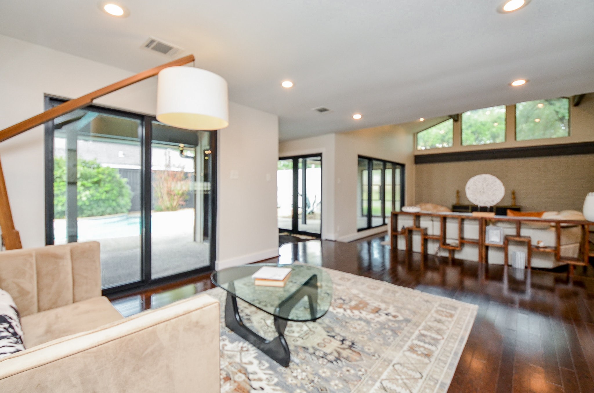 a living room with furniture a large window and wooden floor
